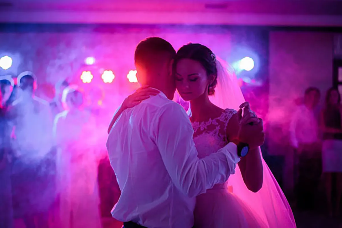 Danse des mariés dans une lumière rose et de la fumée